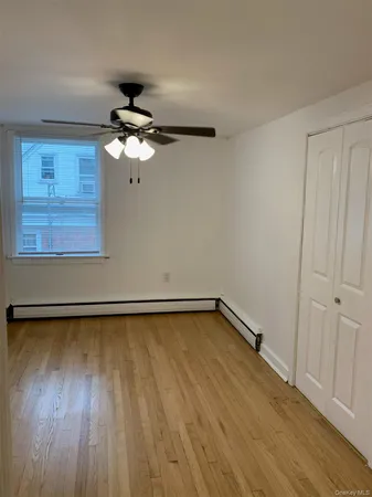 a view of a room with wooden floor a ceiling fan and staircase