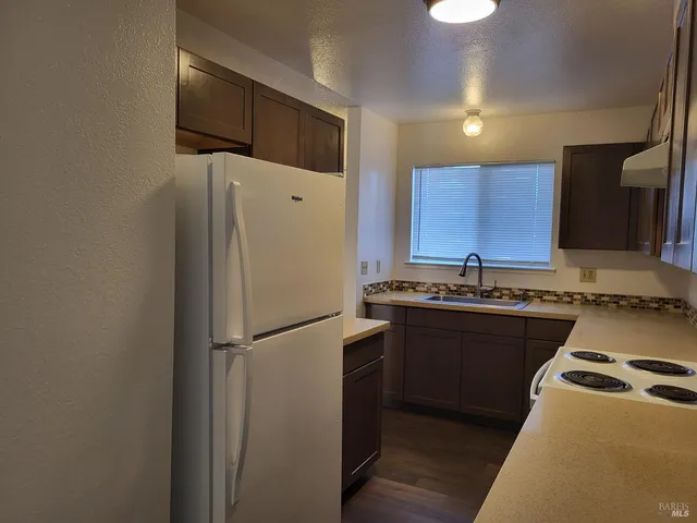 a kitchen with stainless steel appliances granite countertop a refrigerator a sink and a stove