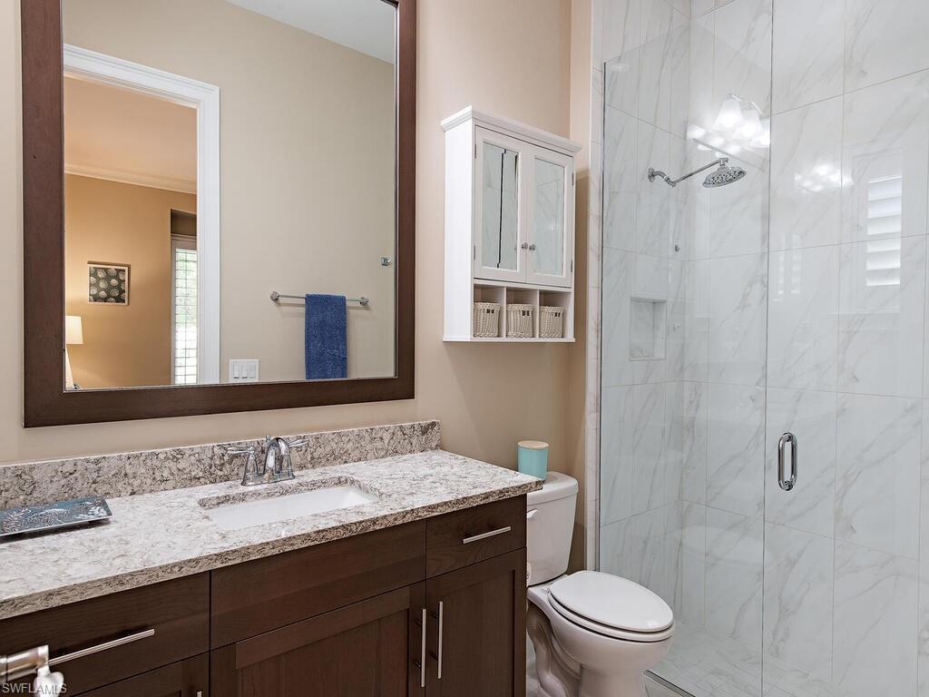 6445 Pembroke Way Naples, FL 34113 - Photo 16 of 40 a bathroom with a granite countertop sink toilet a mirror a shower and a vanity