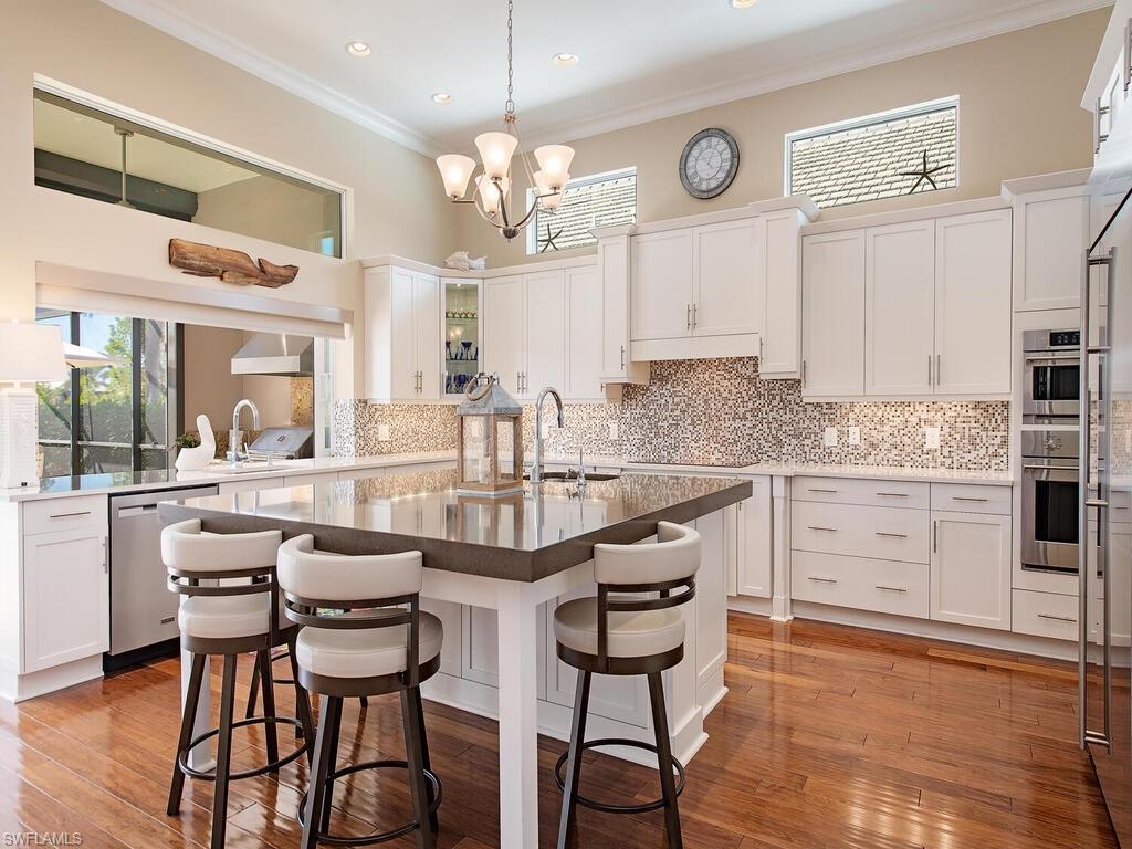 6445 Pembroke Way Naples, FL 34113 - Photo 9 of 40 a kitchen with a table chairs stove and cabinets