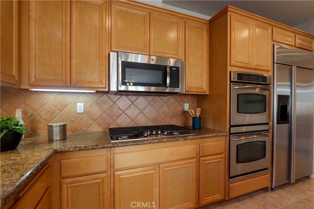 327 Tomko Way Placentia, CA 92870 - Photo 13 of 47 a kitchen with granite countertop cabinets stainless steel appliances and wooden cabinets