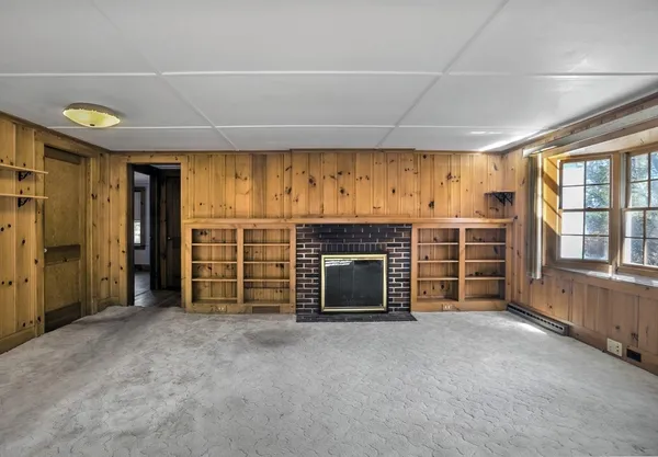 a view of an empty room with a fireplace and a window