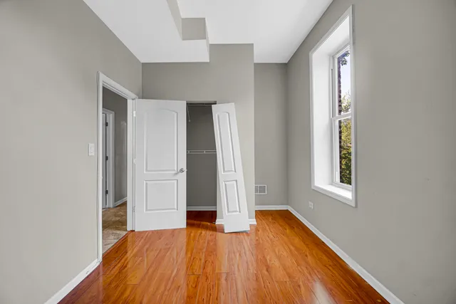 an empty room with wooden floor and windows