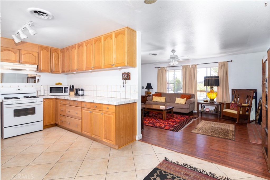 41320 Linda Vista Court Hemet, CA 92544 - Photo 13 of 31 a kitchen with stainless steel appliances granite countertop a stove top oven a sink dishwasher and white cabinets with wooden floor