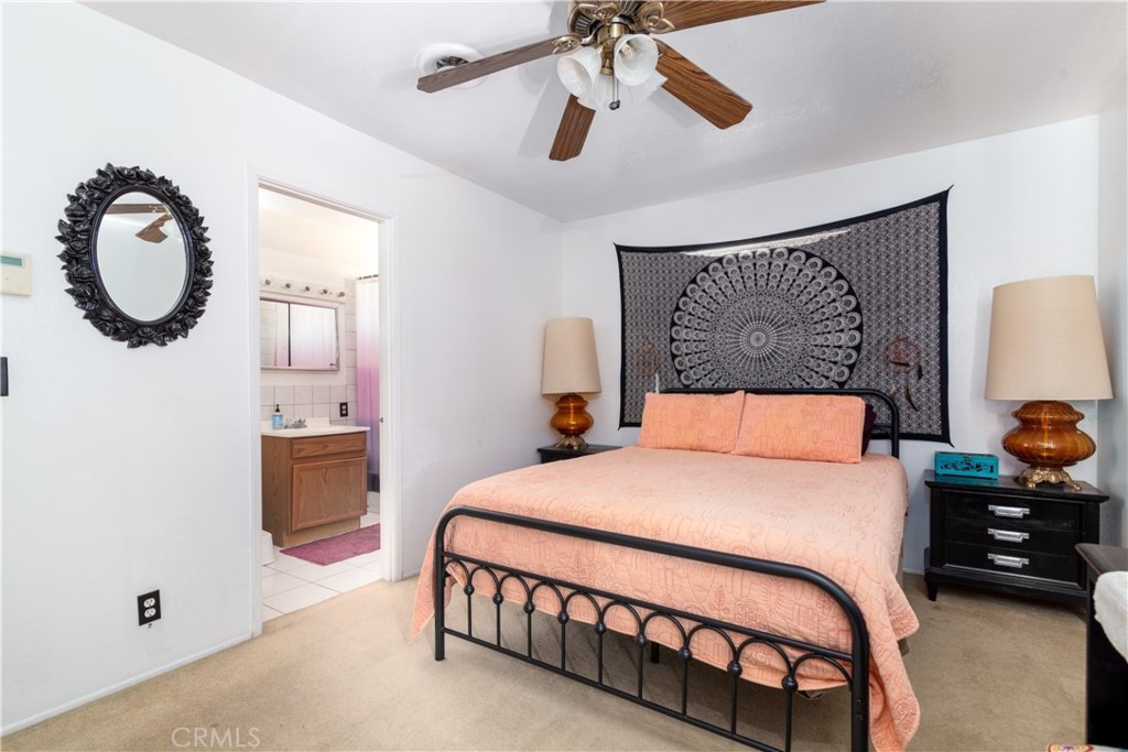 41320 Linda Vista Court Hemet, CA 92544 - Photo 20 of 31 a bedroom with a bed a mirror on dresser and a chandelier