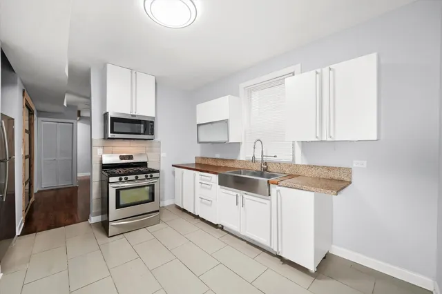 a kitchen with granite countertop white cabinets and stainless steel appliances