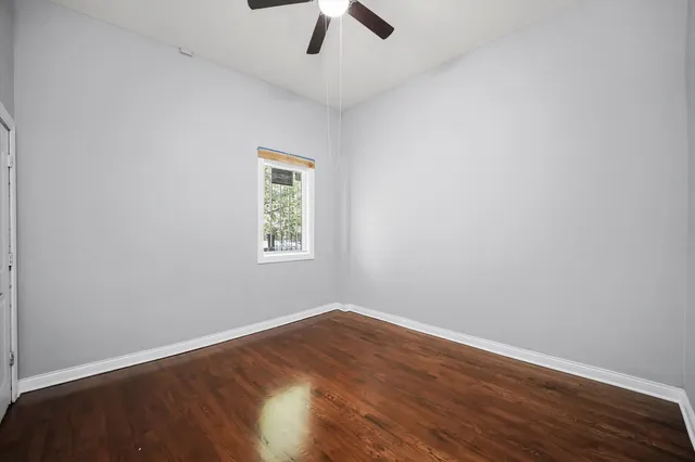 an empty room with a window and a ceiling fan