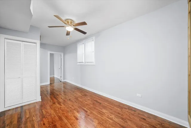 an empty room with wooden floor ceiling fan and windows