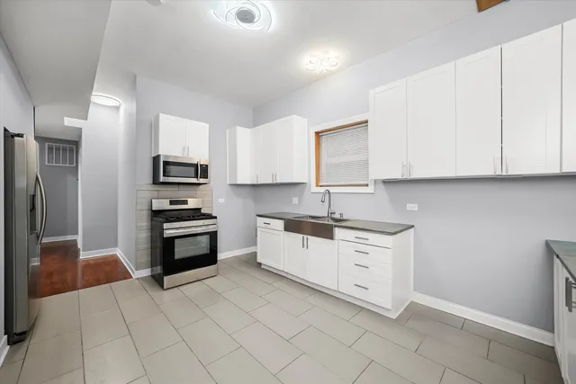 a kitchen with white cabinets stainless steel appliances