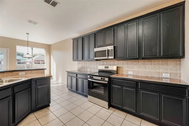 a kitchen with stainless steel appliances granite countertop wooden cabinets a stove top oven a sink and dishwasher