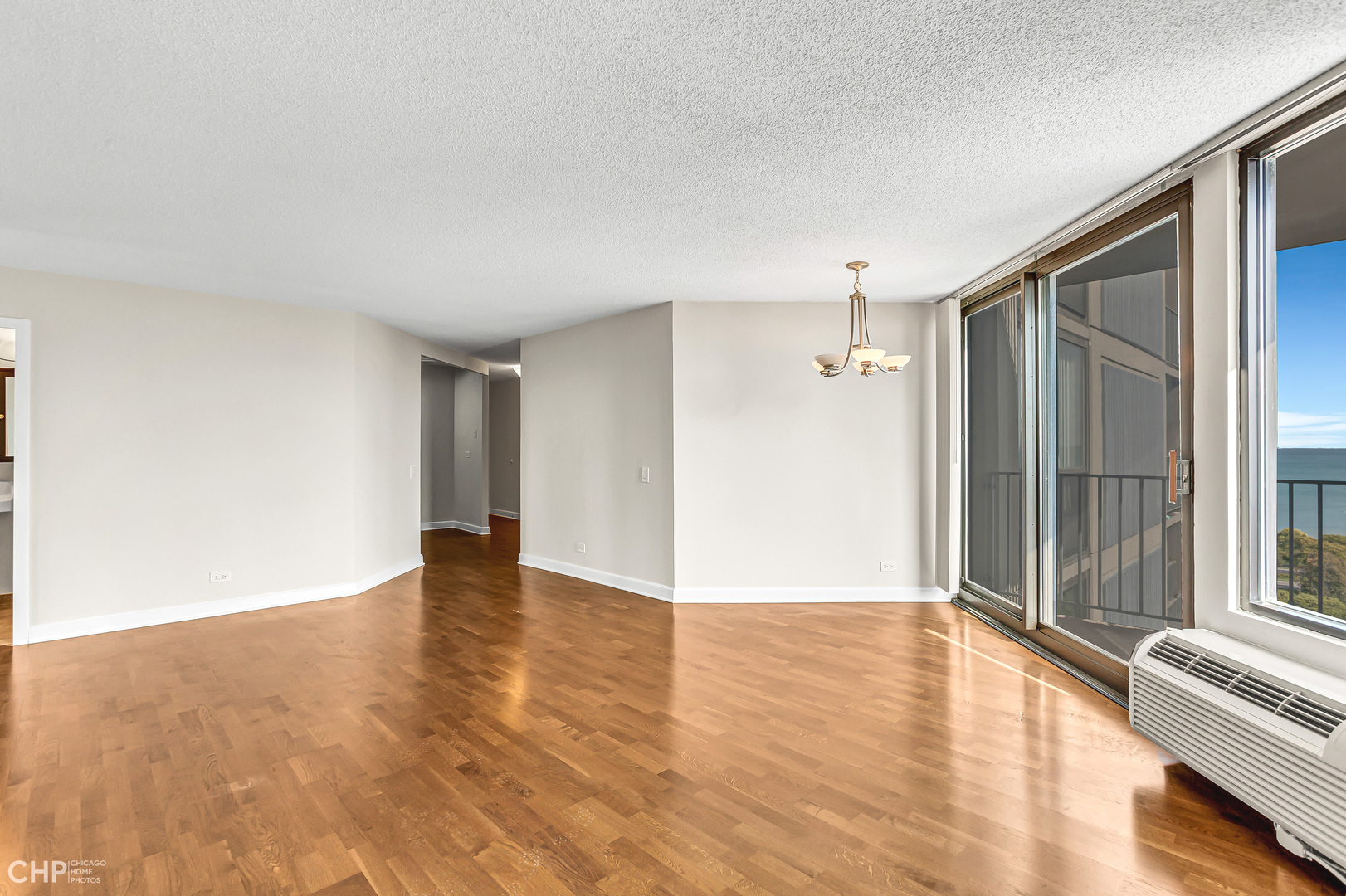 5320 North Sheridan Road, Unit 2002 Chicago, IL 60640 - Photo 6 of 57 a view of an empty room with wooden floor and a window