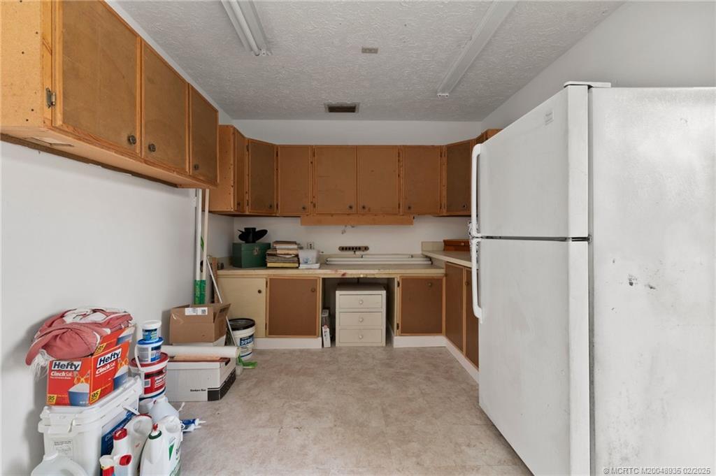 815 Southwest Salerno Road Stuart, FL 34997 - Photo 67 of 71 a kitchen with a refrigerator and white cabinets