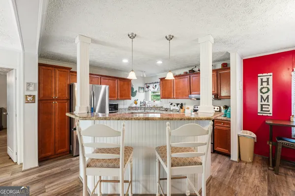 a kitchen with stainless steel appliances a dining table chairs refrigerator and sink