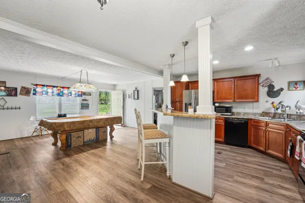 a kitchen with stainless steel appliances granite countertop a table chairs sink and cabinets