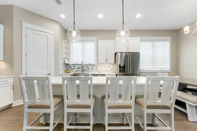 a kitchen with kitchen island granite countertop a table chairs refrigerator and microwave