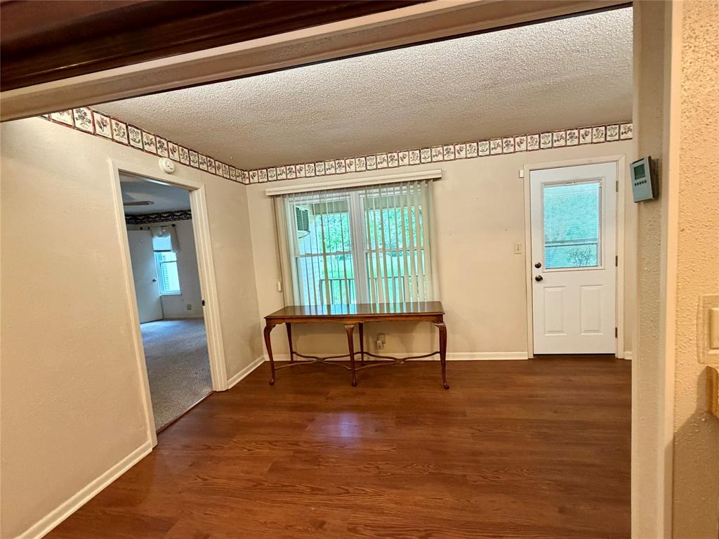 2030 Sycamore Street Paris, TX 75460 - Photo 5 of 24 Room featuring wood-finish flooring, a white paneled door with a window, and a window with vertical blinds