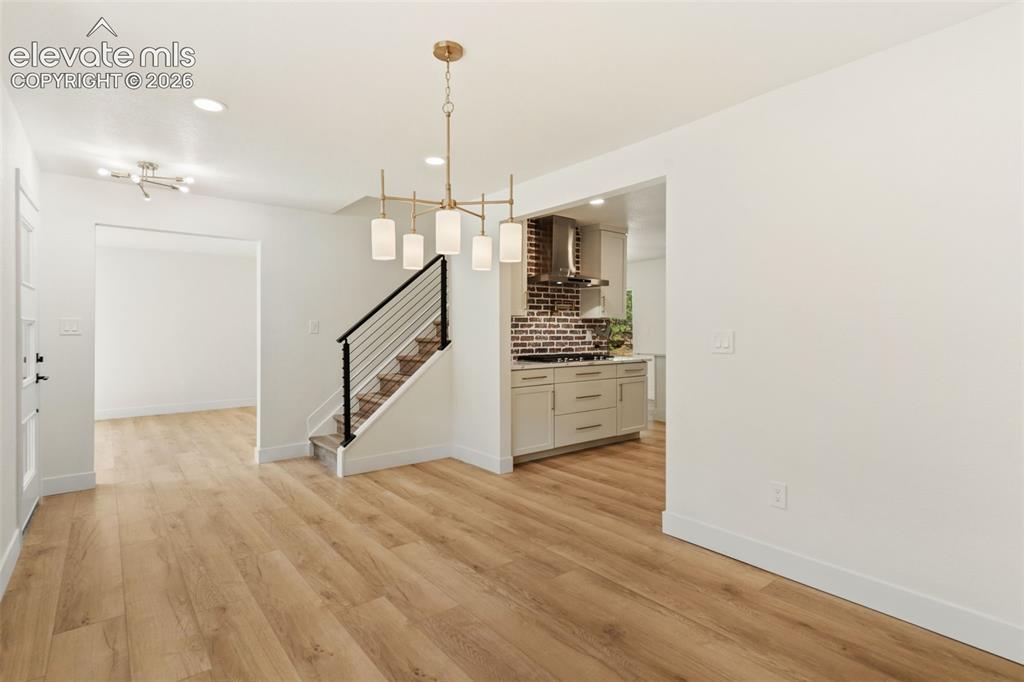 11665 Greentree Road Colorado Springs, CO 80908 - Photo 7 of 43 Unfurnished dining area with light wood-style floors, recessed lighting, a chandelier, and stairway