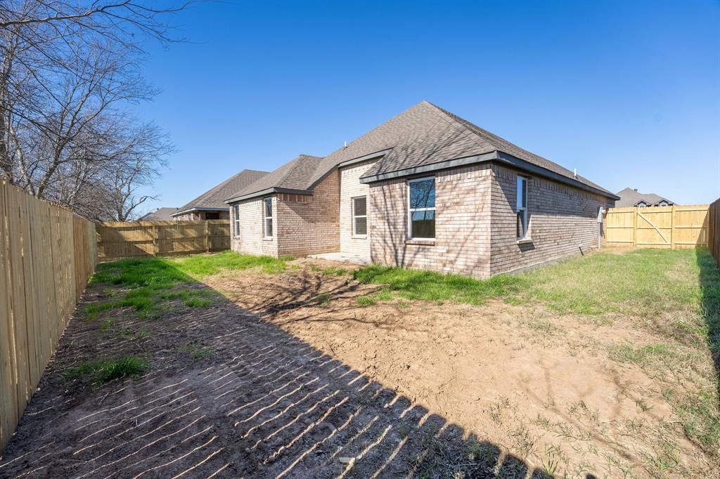 1032 Springview Lane Mabank, TX 75147 - Photo 15 of 15 Back of property with a fenced backyard, brick siding, and roof with shingles