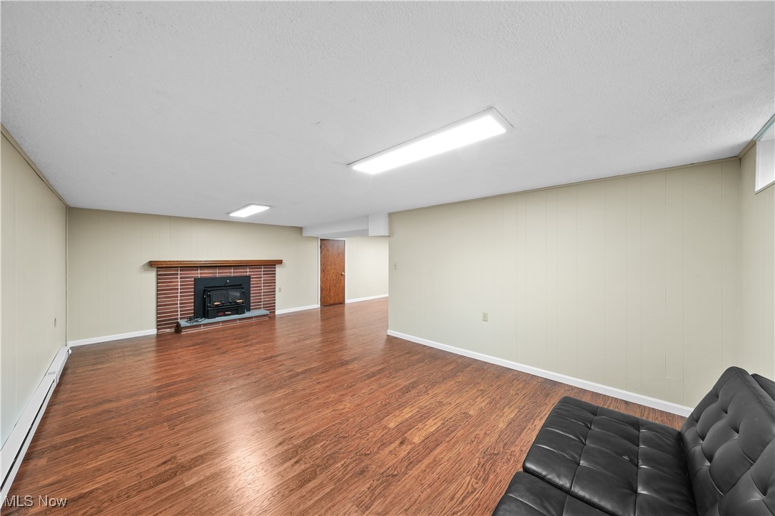 10 Kehner Road Mogadore, OH 44260 - Photo 21 of 32 Unfurnished living room with a baseboard heating unit, a textured ceiling, and hardwood / wood-style flooring