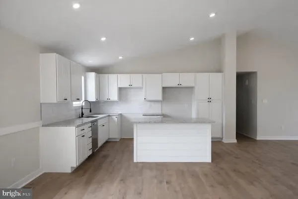 a kitchen with stainless steel appliances a sink a stove a refrigerator and white cabinets