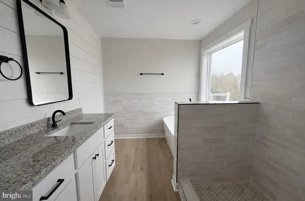 a bathroom with a granite countertop sink mirror and a bathtub