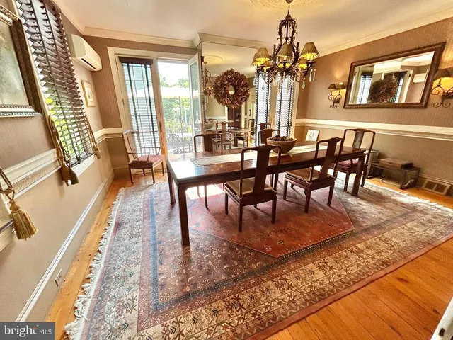 a view of a dining room and livingroom with furniture wooden floor a rug a fireplace and a chandelier