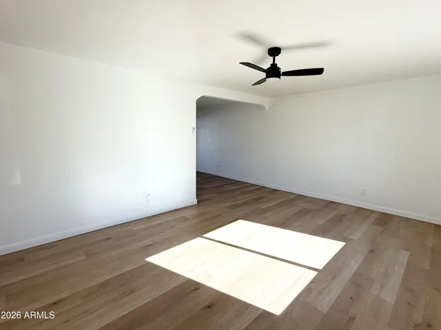 an empty room with wooden floor a ceiling fan and wooden floor
