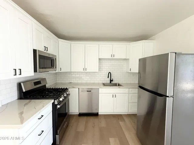 a kitchen with a refrigerator sink and white cabinets