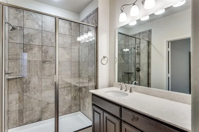 a bathroom with a granite countertop sink a mirror and a shower