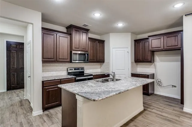 a kitchen with stainless steel appliances granite countertop a sink stove microwave and refrigerator