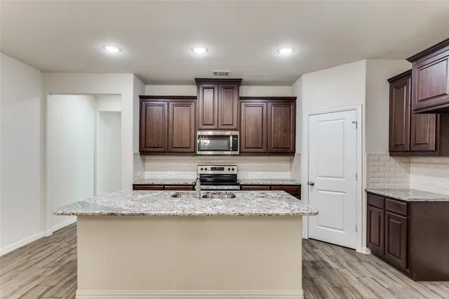 a kitchen with granite countertop stainless steel appliances and wooden cabinets