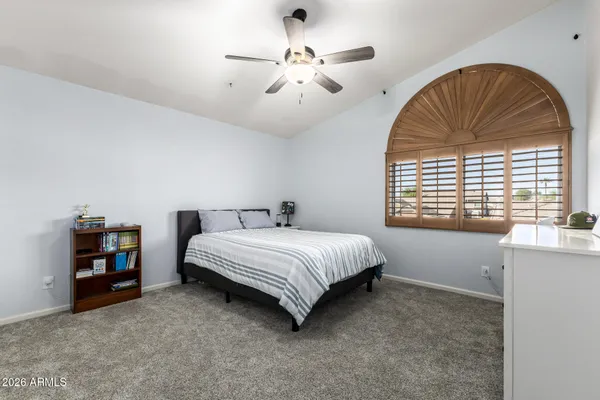 a spacious bedroom with a bed a table and windows