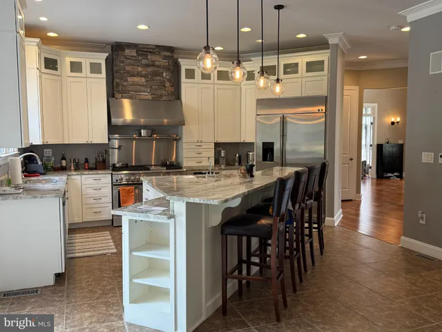 a kitchen with kitchen island granite countertop a table chairs sink and cabinets
