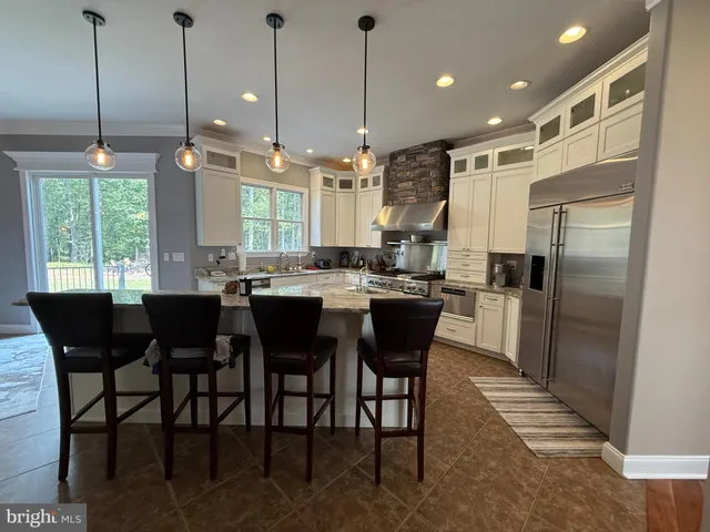 a kitchen with stainless steel appliances kitchen island granite countertop a refrigerator a sink a dining table and chairs