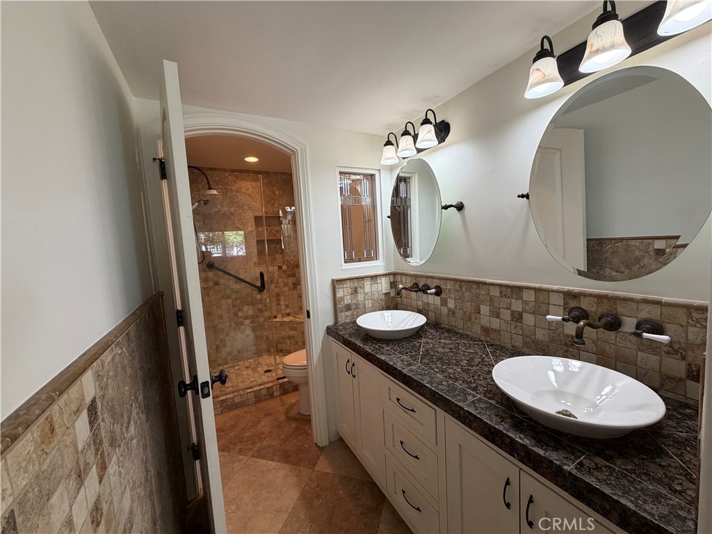 34132 Selva Road, Unit 250 Dana Point, CA 92629 - Photo 13 of 25 a bathroom with a granite countertop sink a mirror and shower