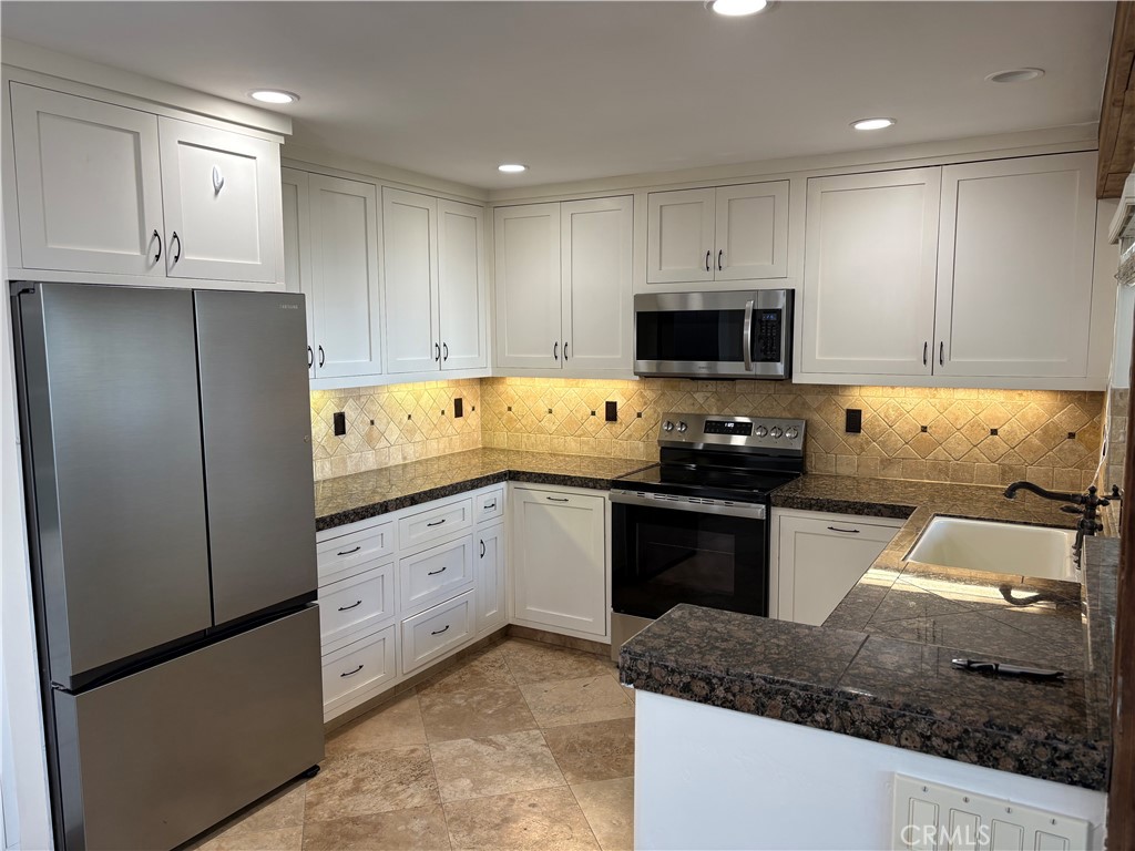 34132 Selva Road, Unit 250 Dana Point, CA 92629 - Photo 4 of 25 a kitchen with granite countertop a stove sink and cabinets