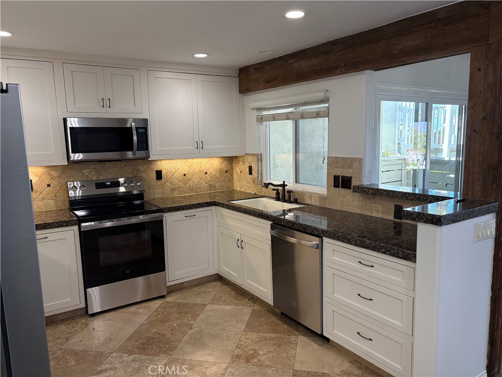 34132 Selva Road, Unit 250 Dana Point, CA 92629 - Photo 5 of 25 a kitchen with granite countertop white cabinets and stainless steel appliances