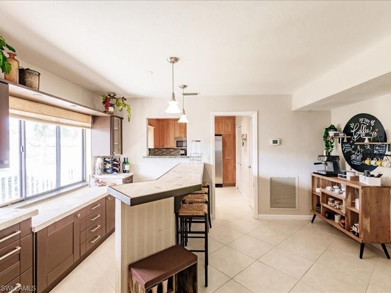 910 Vanderbilt Beach Road, Unit 524W Naples, FL 34108 - Photo 19 of 44 Kitchen with a breakfast bar, appliances with stainless steel finishes, decorative light fixtures, and light tile floors