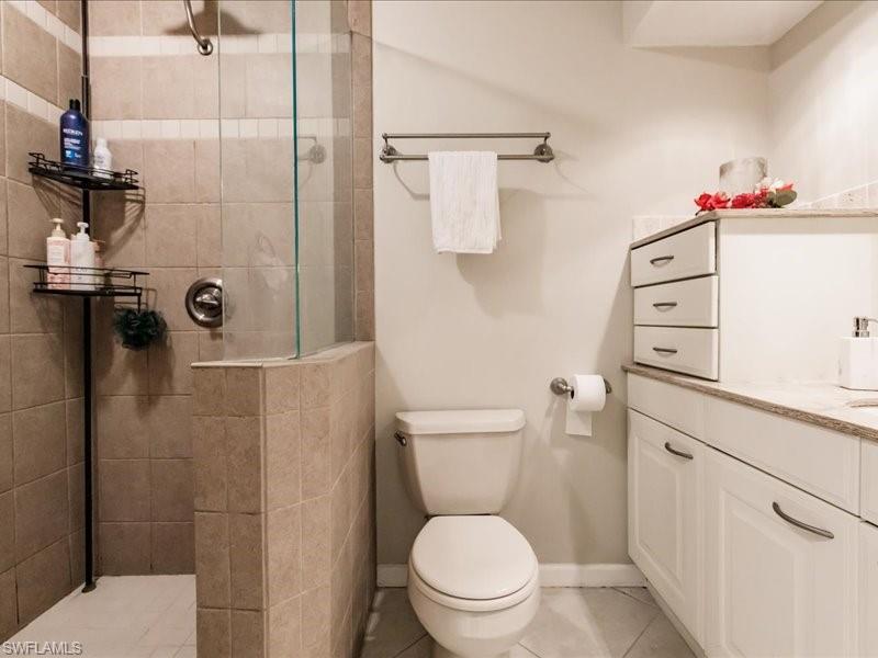 910 Vanderbilt Beach Road, Unit 524W Naples, FL 34108 - Photo 25 of 44 Bathroom with tile floors, a shower with door, toilet, and vanity