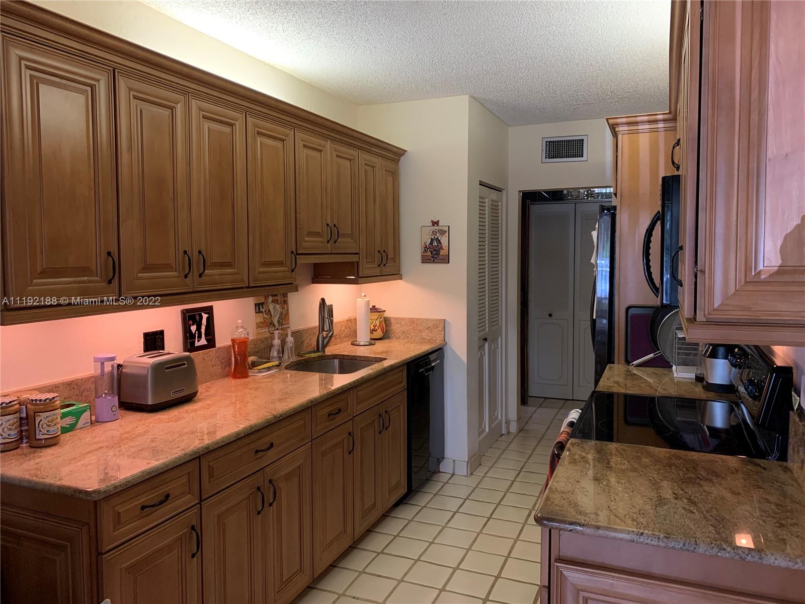 6328 Longboat Lane West, Unit 104 Boca Raton, FL 33433 - Photo 2 of 4 a kitchen with stainless steel appliances granite countertop a sink stove and refrigerator