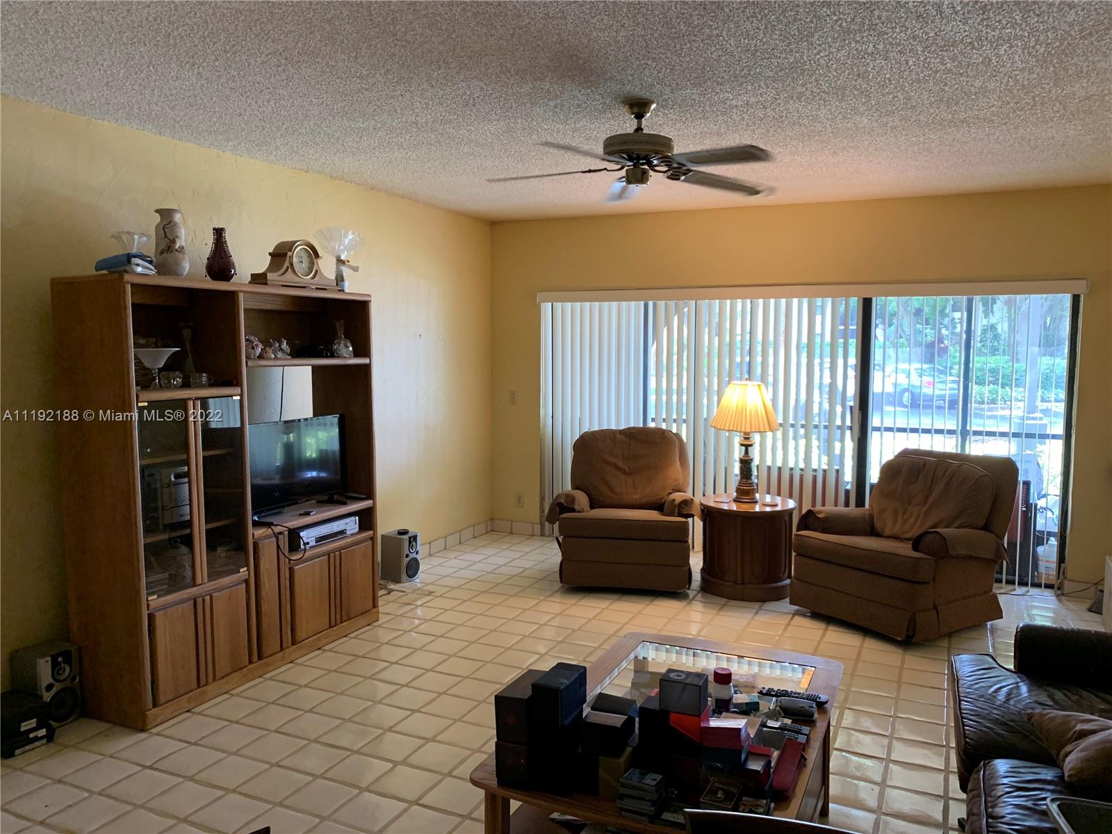 6328 Longboat Lane West, Unit 104 Boca Raton, FL 33433 - Photo 3 of 4 a living room with furniture a flat screen tv and a window