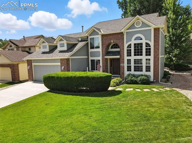 a view of a white house with a big yard and potted plants