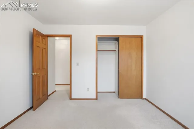 a view of an empty room with closet and a window