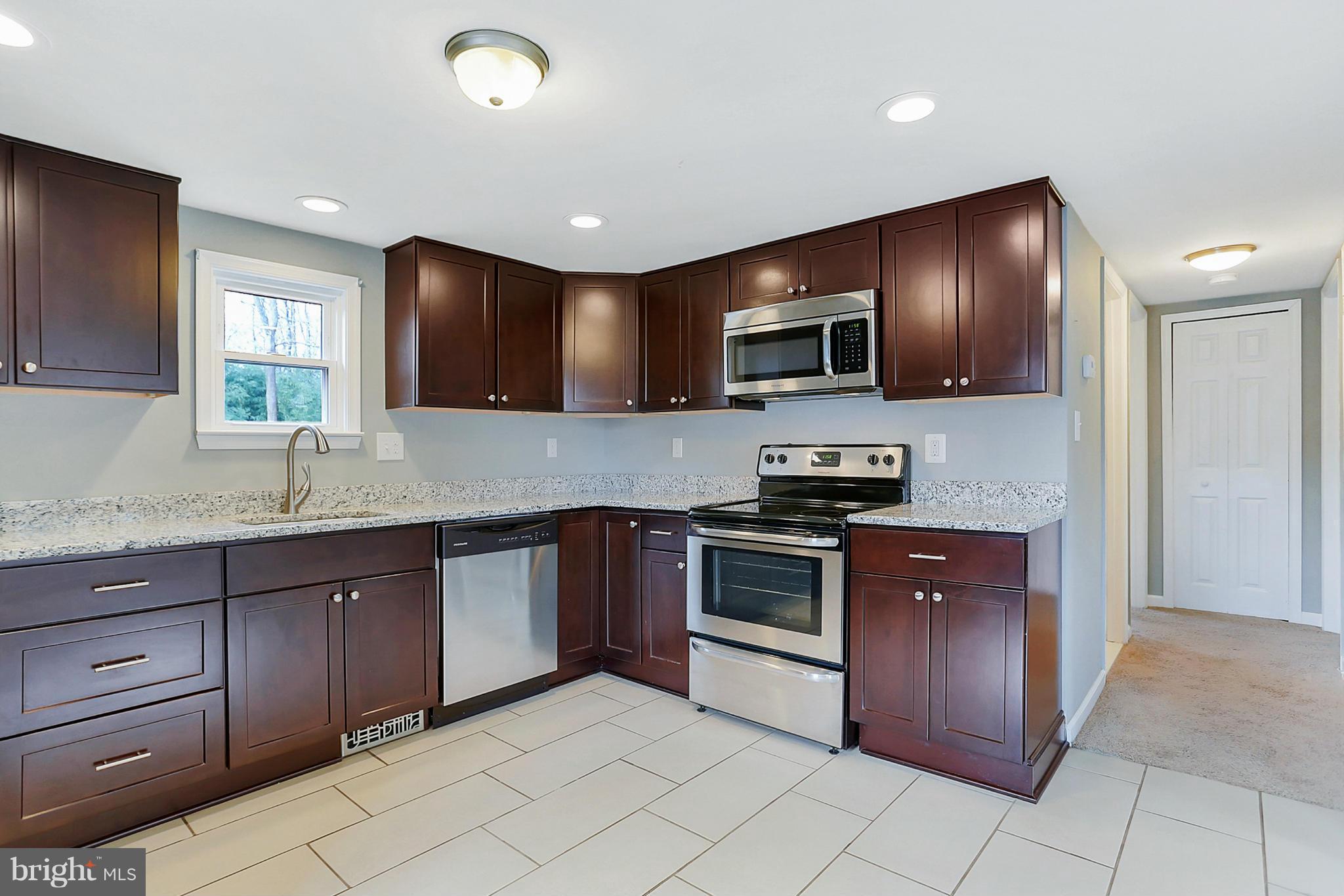 220 W Road Baltimore, MD 21221 - Photo 8 of 30 a kitchen with stainless steel appliances granite countertop wooden cabinets a stove top oven a sink and dishwasher