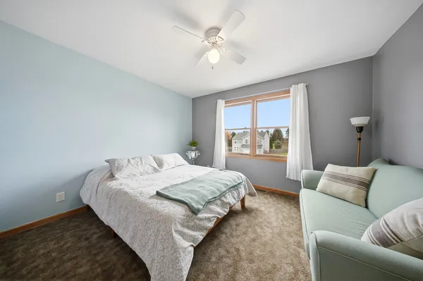 a bedroom with a large bed couch and window