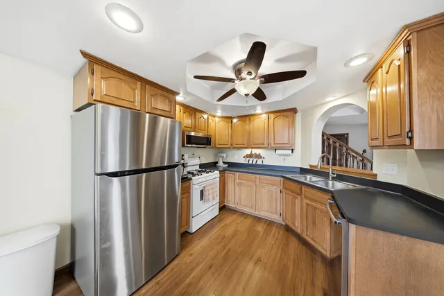 a kitchen with stainless steel appliances a refrigerator a sink and white cabinets