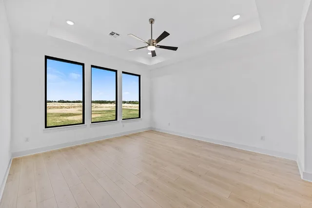 an empty room with windows and ceiling fan