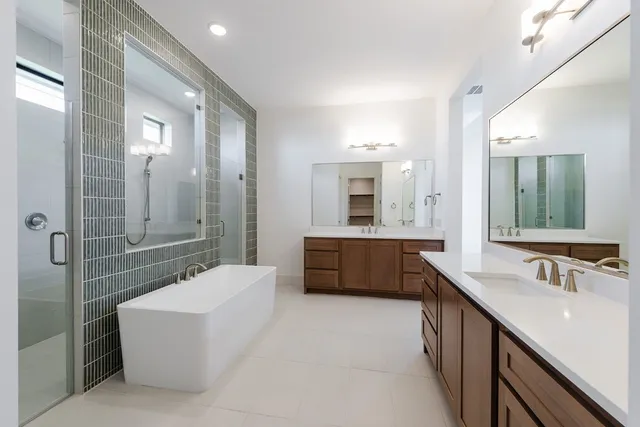 a bathroom with a tub a double vanity sink and mirror