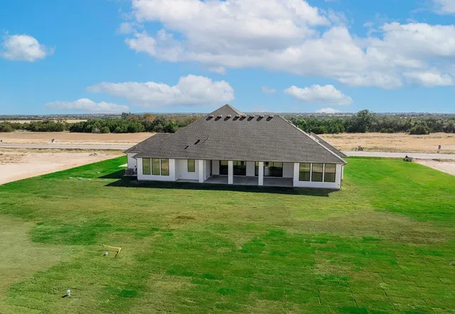 a aerial view of a house next to big yard with big trees