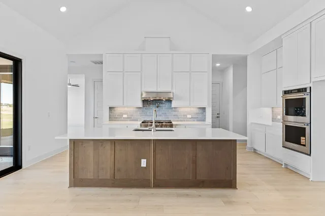 a large kitchen with stainless steel appliances granite countertop a stove a sink and a refrigerator